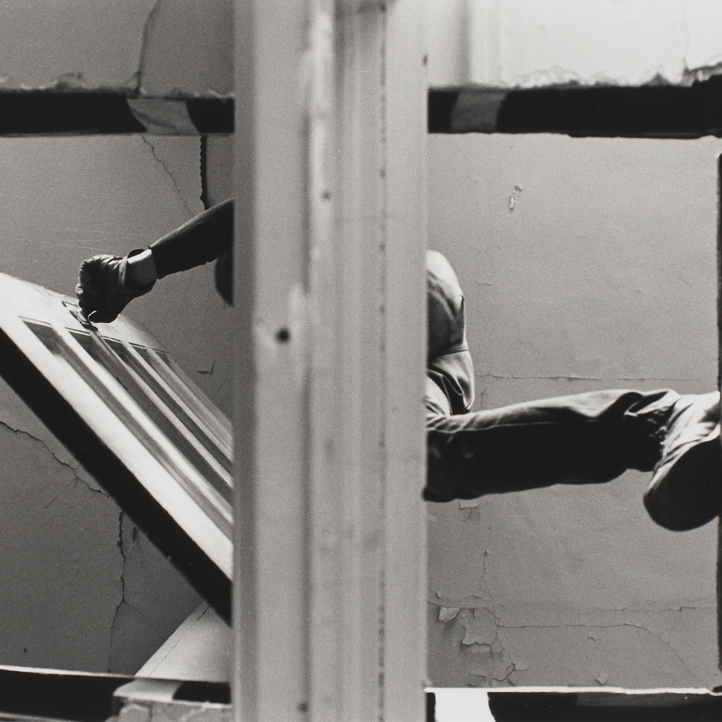 Black and white photograph of a cut out in the floor with a man stepping over