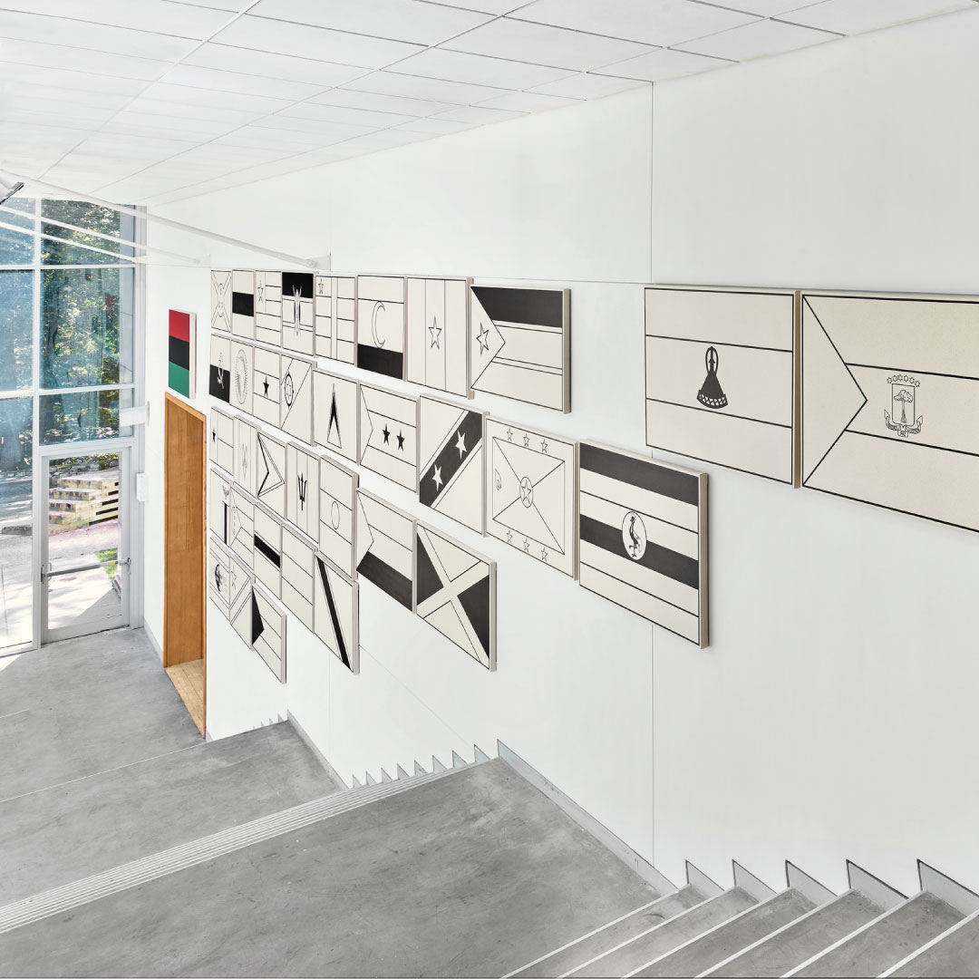 Installation view of the Lois Foster Stairwell with a selection of flag paintings by the artist Fred Wilson on the wall.