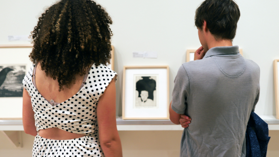 Two students look at art works on a shelf in the Lee Gallery at the Rose Art Museum