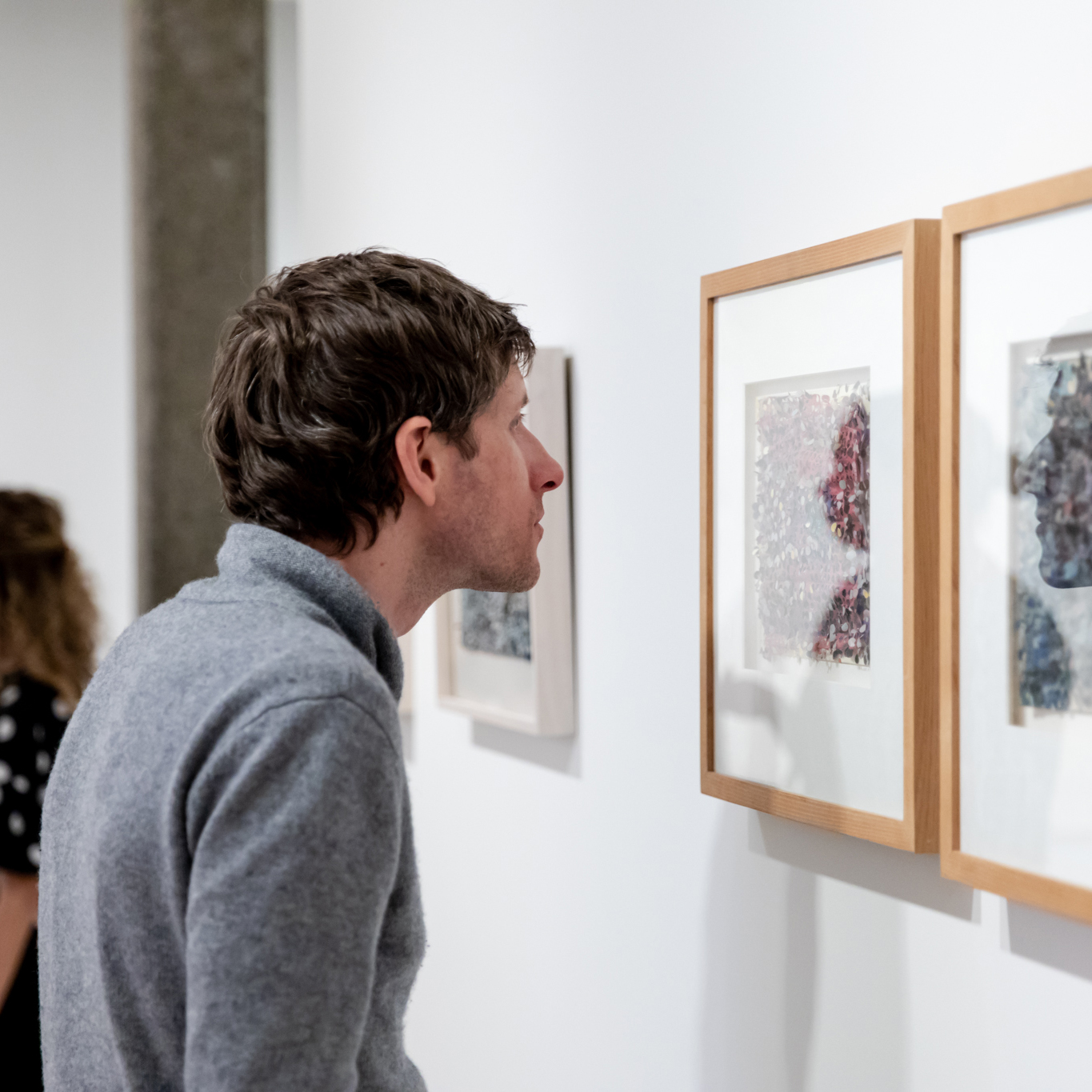 Visitor leaning in closely to look at a Howardena Pindell work on view at the Rose.