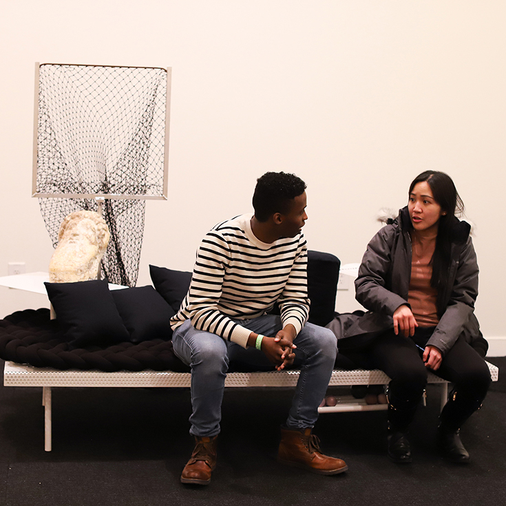 Two visitors sitting on a modular day bed. 