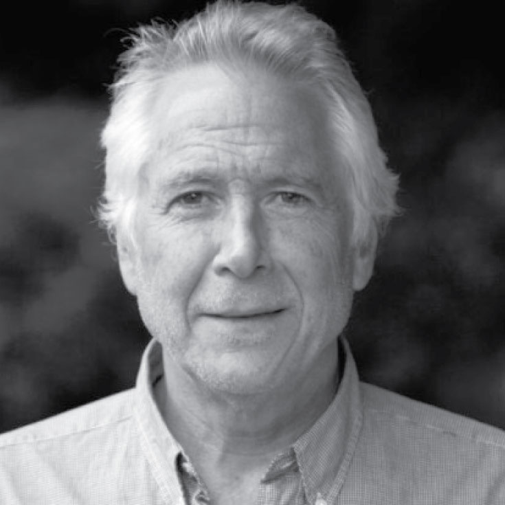 Black and white photo of a white man with white hair wearing a collared shirt.