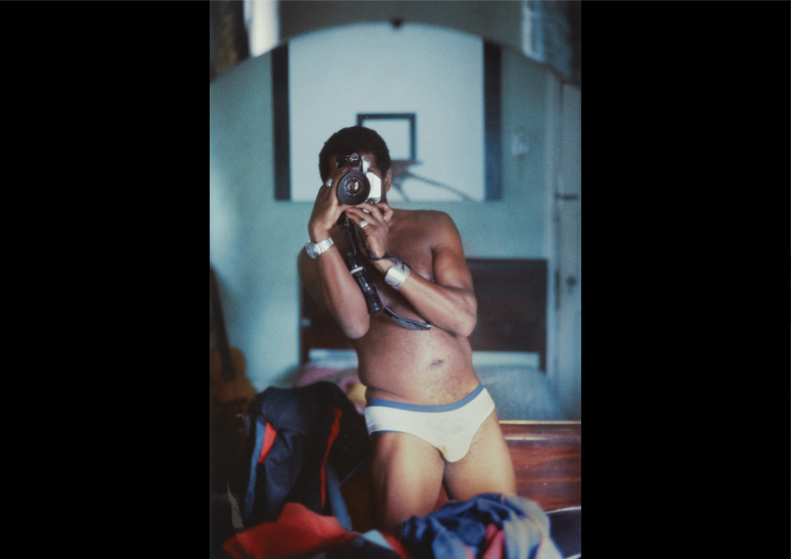 Self portrait of Barkley L. Hendricks in his underwear with a camera covering his face. 