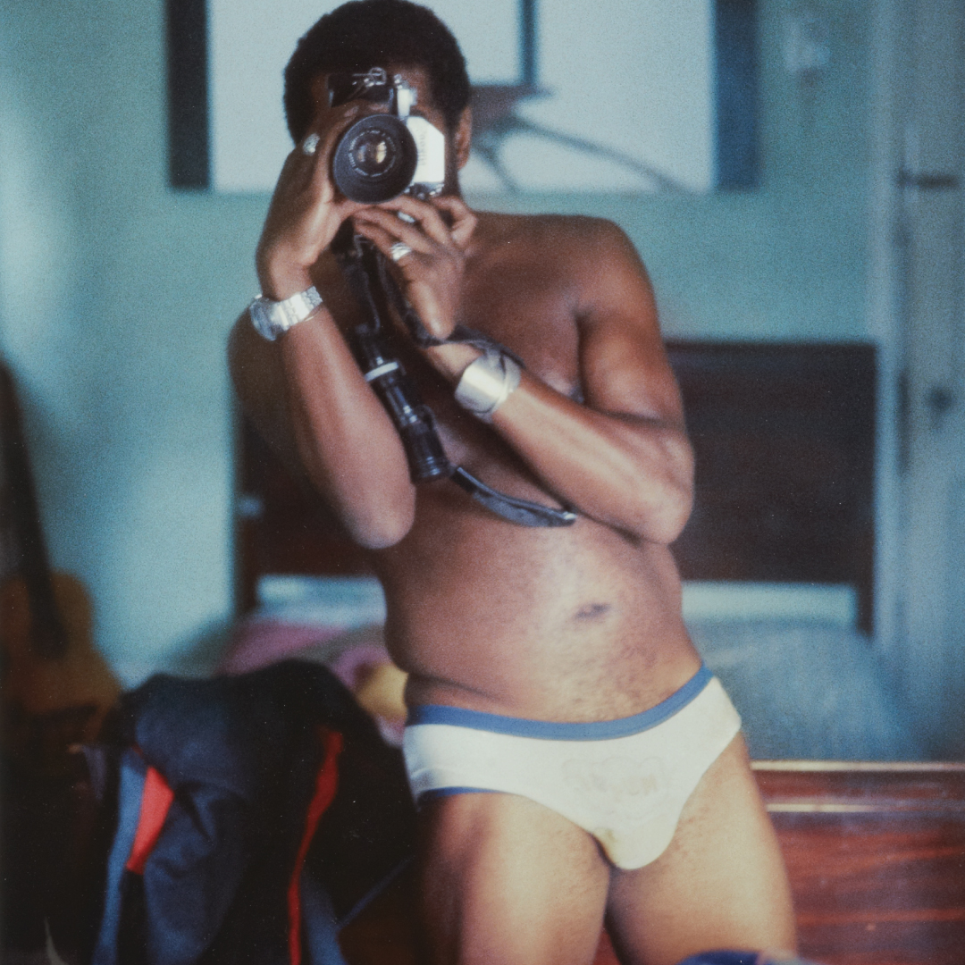 Self portrait of Barkley L. Hendricks in his underwear with a camera covering his face. 