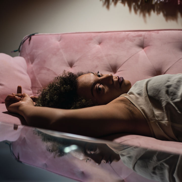 A woman laying on a couch looking at the camera