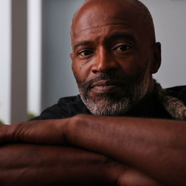 A black man resting his head on his folded arms