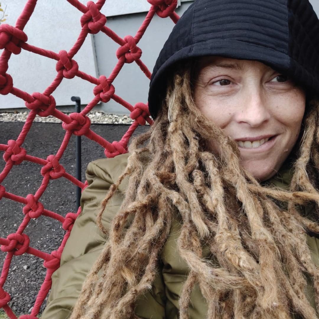 A woman against a red chain-linked fence