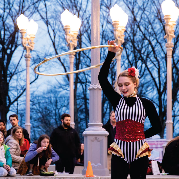 A woman circus performer performs with a hula hoop at Light of Reason..