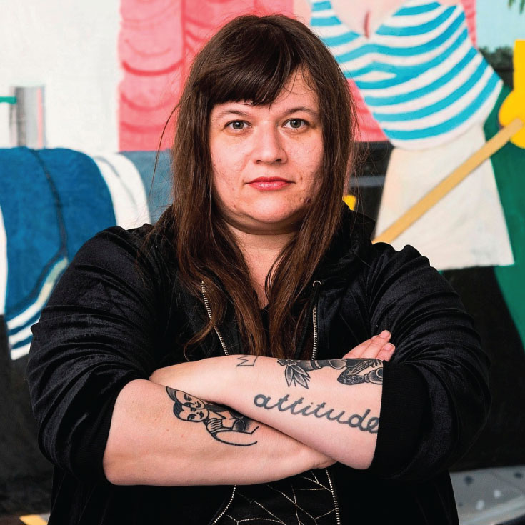 A woman stands in front of a painting