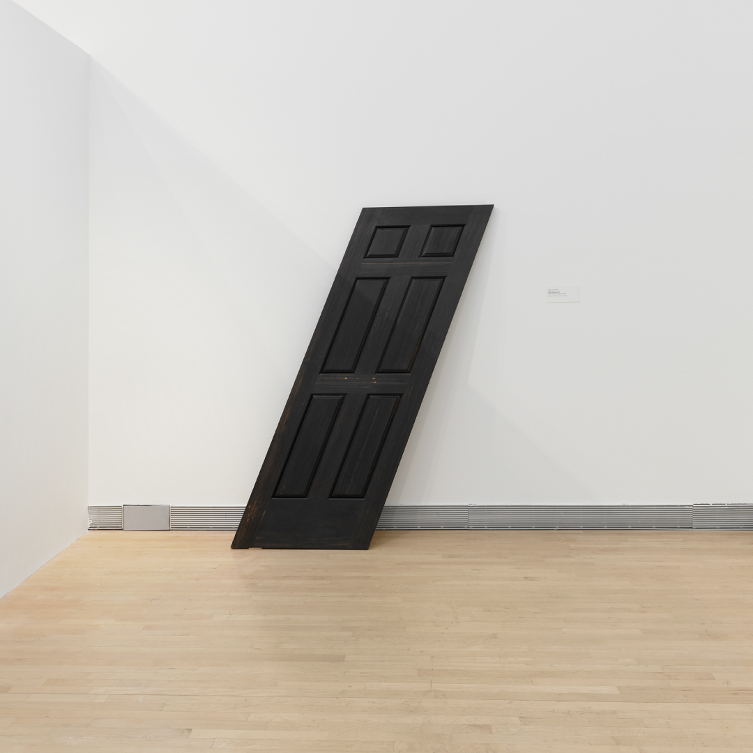 A slanted door against a white wall