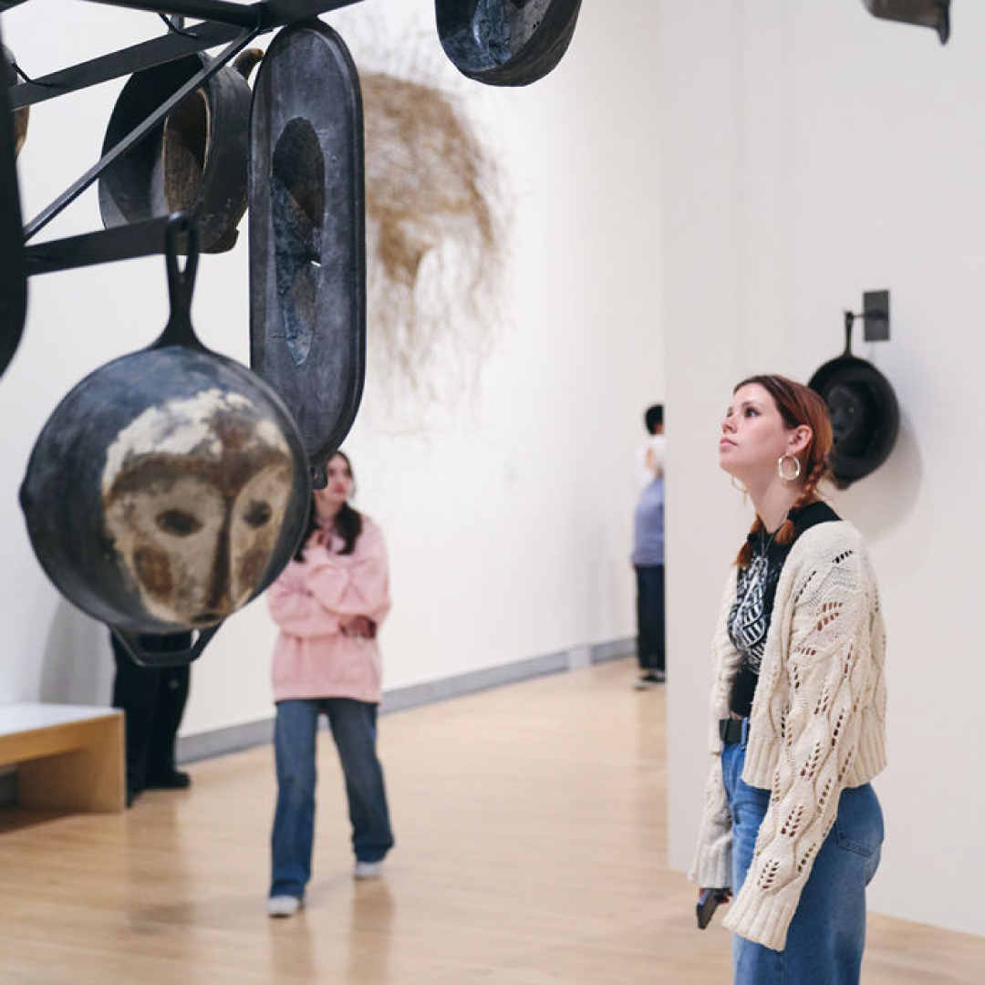 A young woman looking at a sculpture by Hugh Hayden
