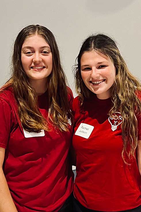 two UDRs stand in red shirts at academic fair