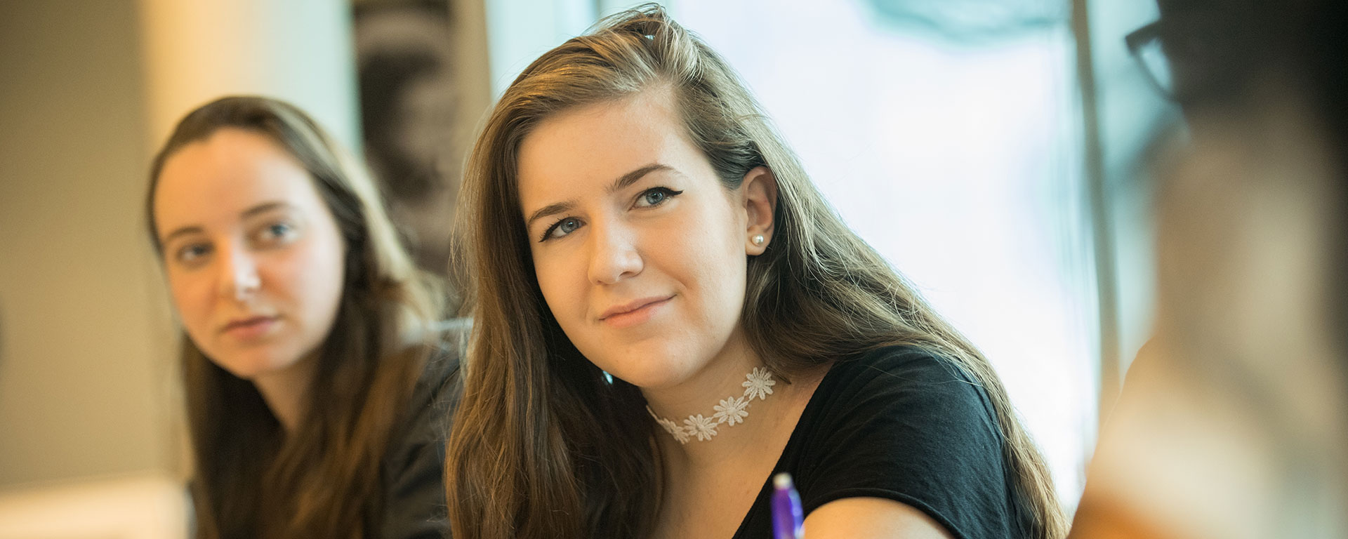 A student smiles slightly as she looks to another member of the class