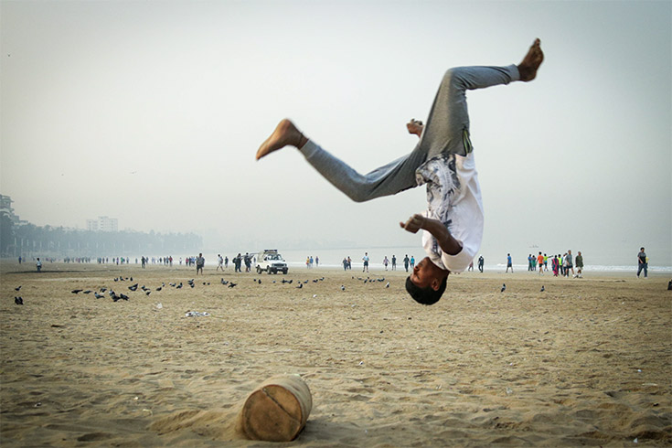 Man upside-down mid-jump on a beach