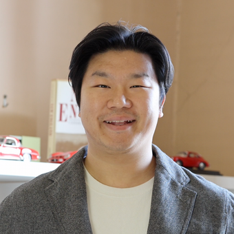Headshot of a smiling Asian man wearing a white casual shirt and gray suit jacket