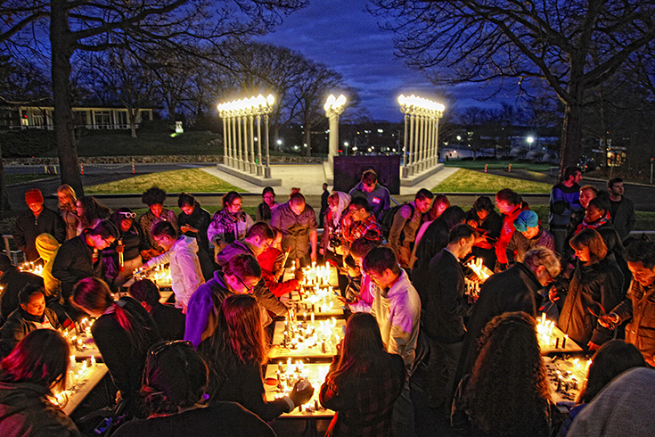 evening shot of people standing around lit candles