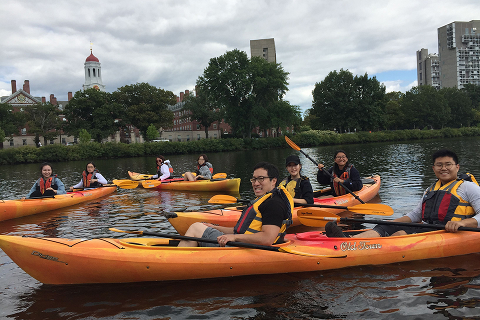 smiling people in long kayaks on a river