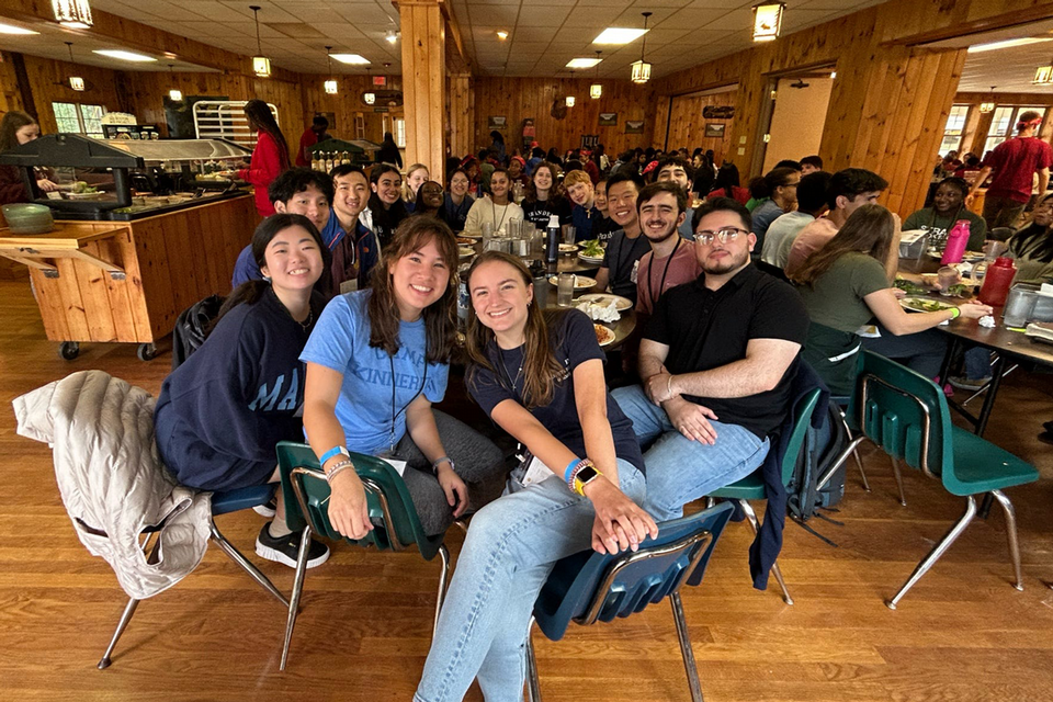 a large group of young men and women in a restaurant sitting around a table and smiling at the camera