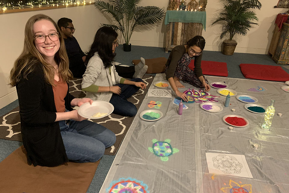 photo of a few students on the floor creating pictures with colored powder