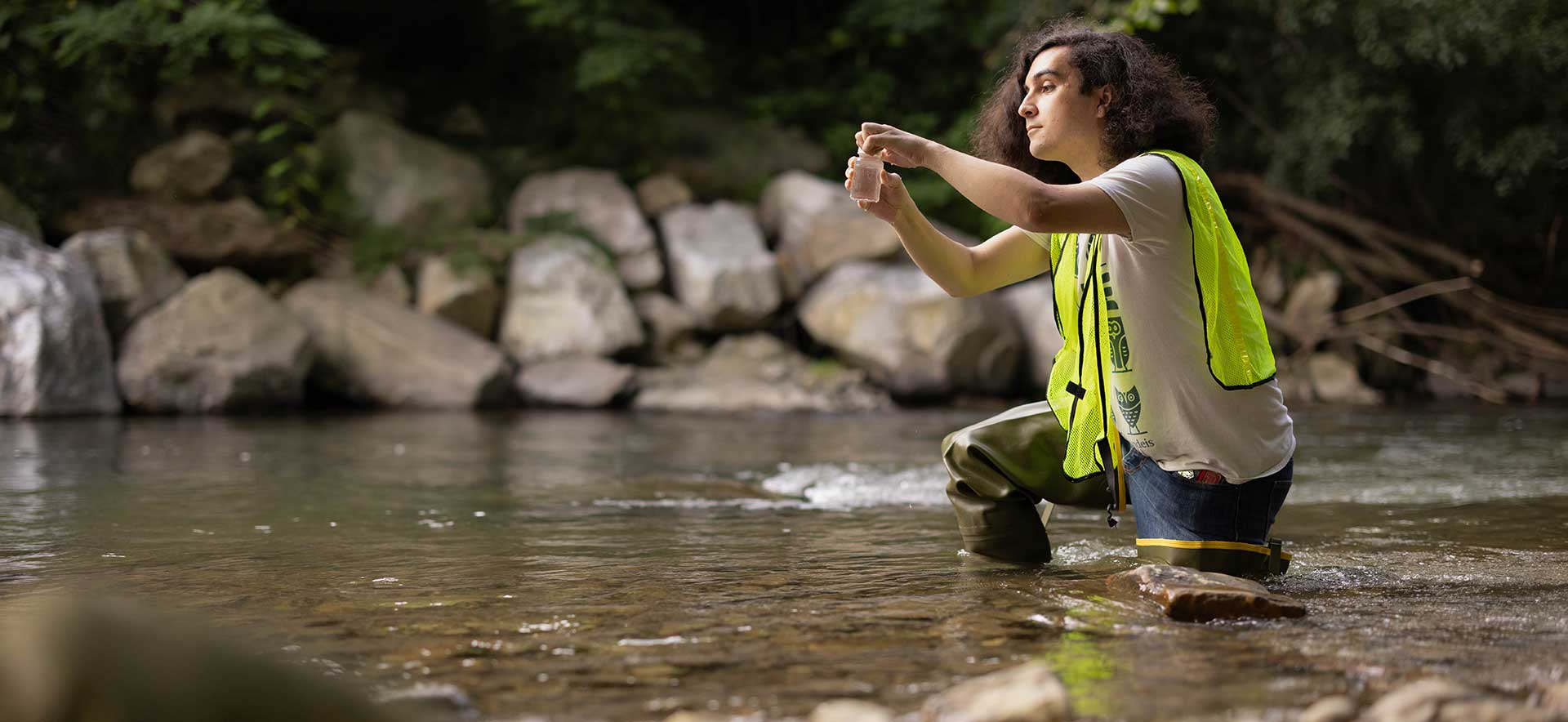 Forman in a river collecting a water sample