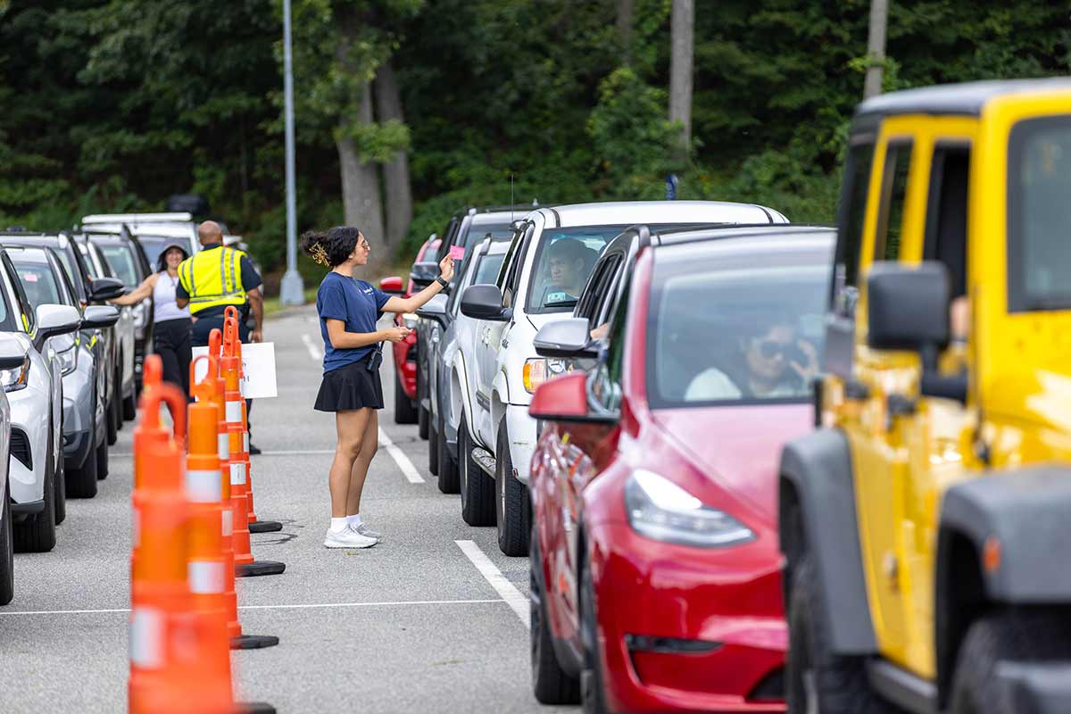 Person directing cars in a parking lot on move-in day