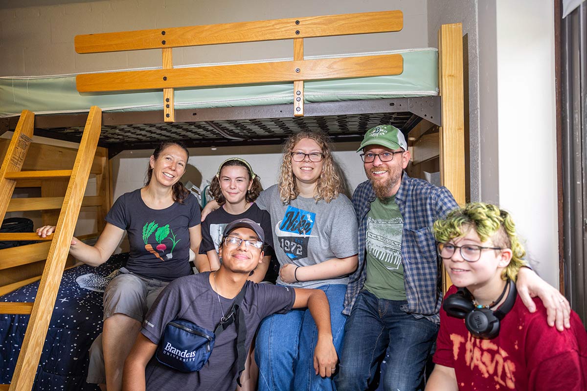 A family seated on a bunk bed in a residence hall