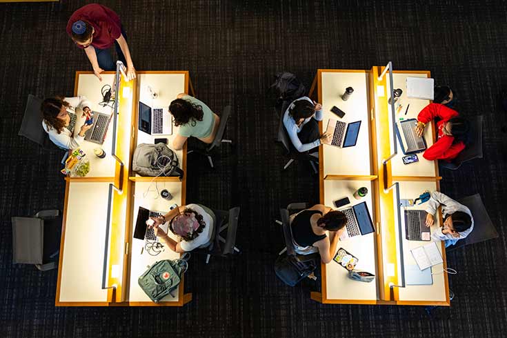 Overhead of students seated at tables working on computers