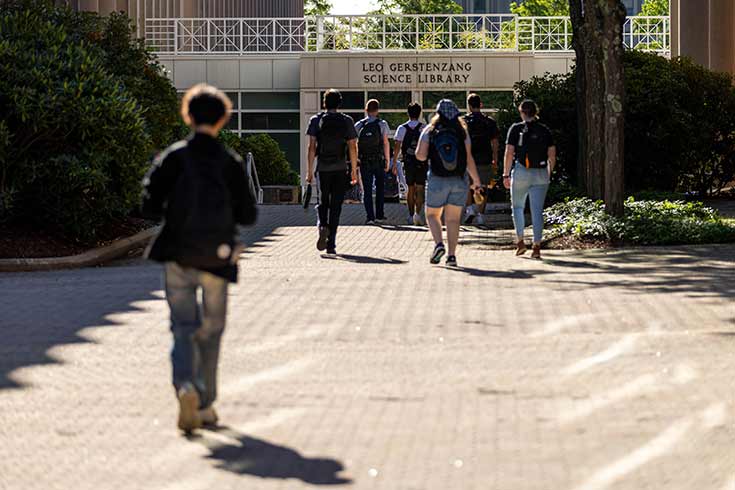 Students walk on campus toward an academic building entrance