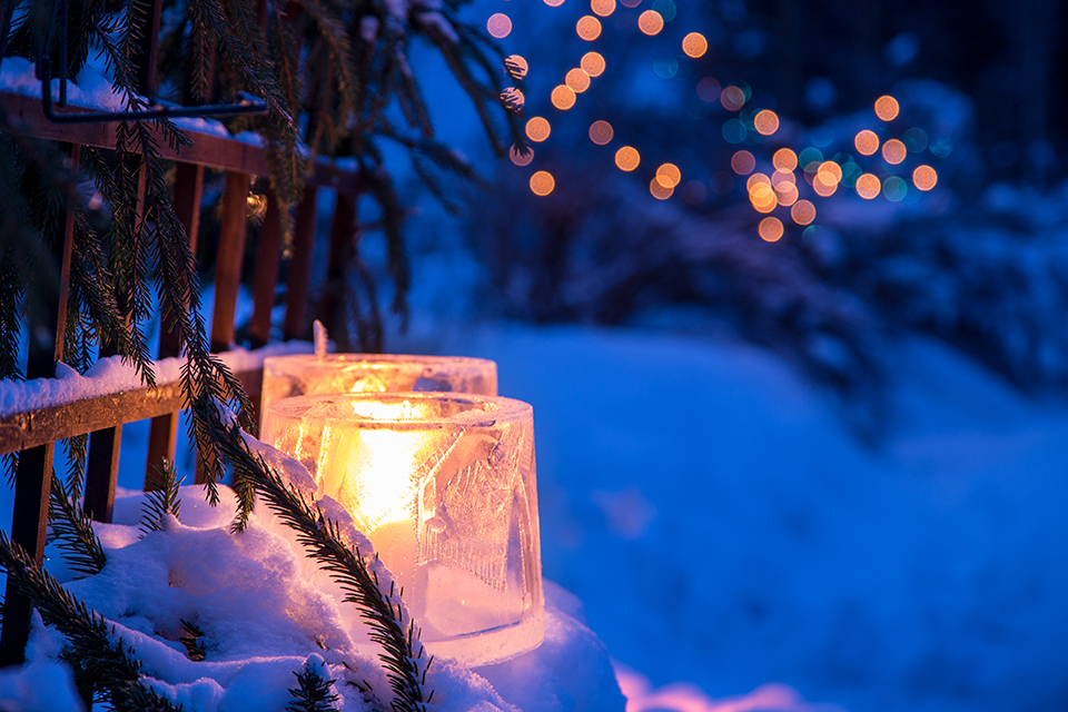 Two burning candles surrounded by snowy landscape at night