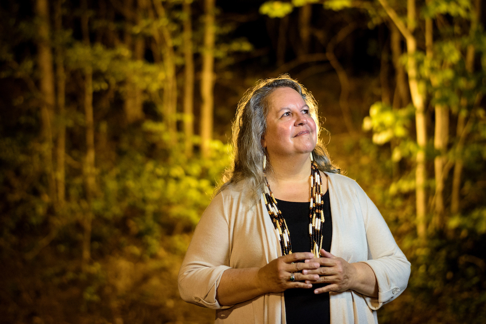 Robin Wall Kimmerer stands in the woods