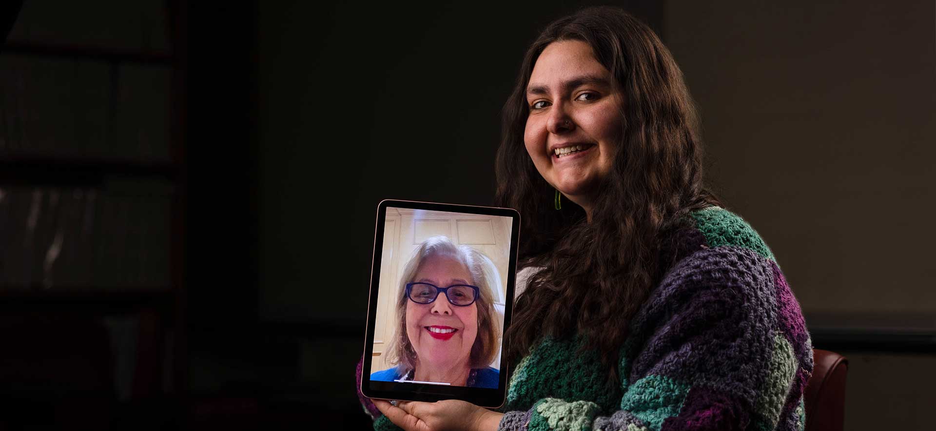 Jessie holds an iPad with her grandmother on it