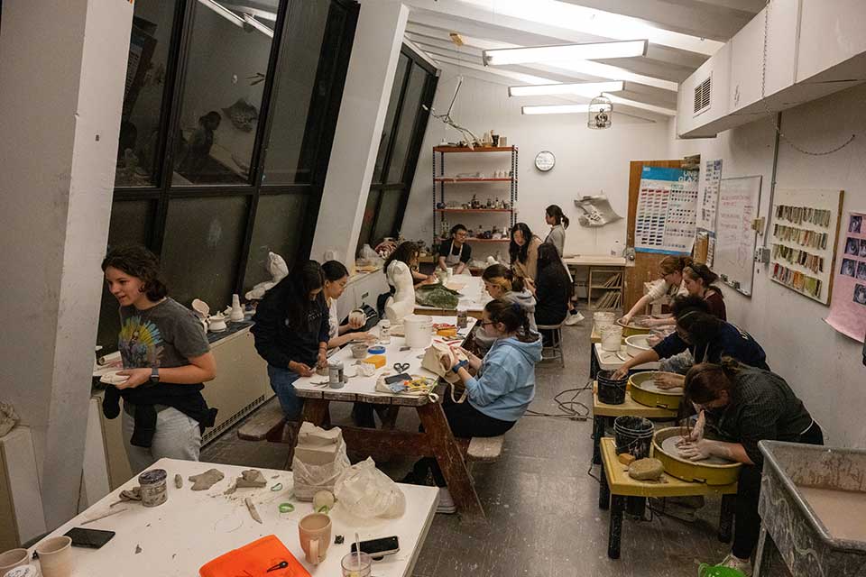 A student sitting at a pottery wheel