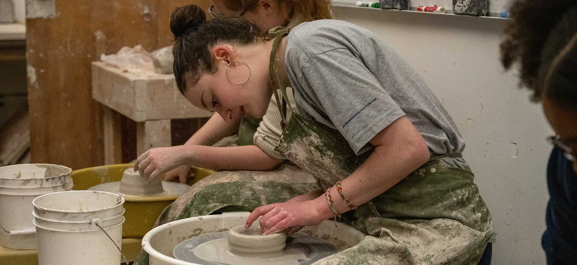 A student sitting at a pottery wheel