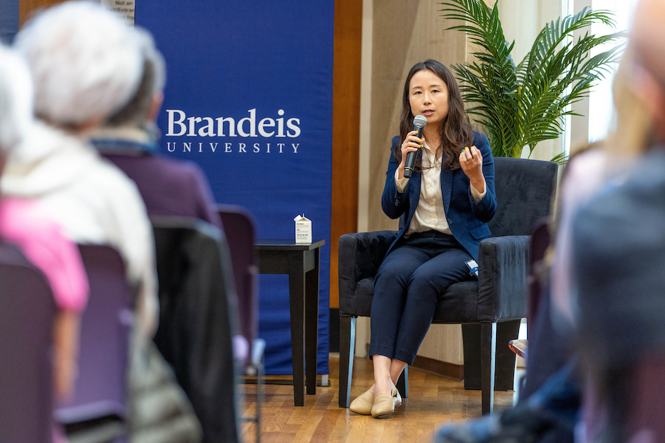 Grace Han speaking at a panel in front of a blue Brandeis banner