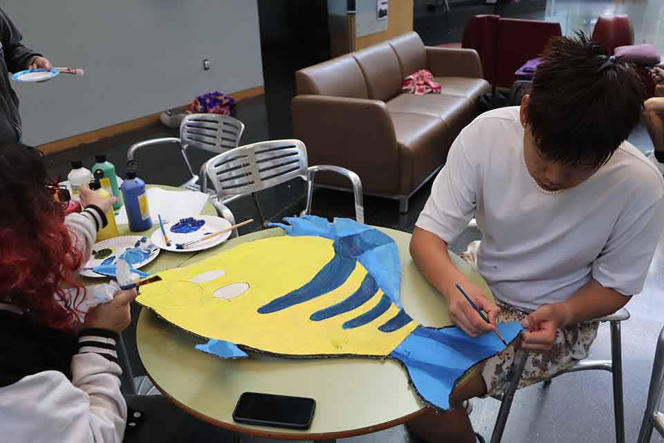 Person paints Flounder, a yellow and blue fish