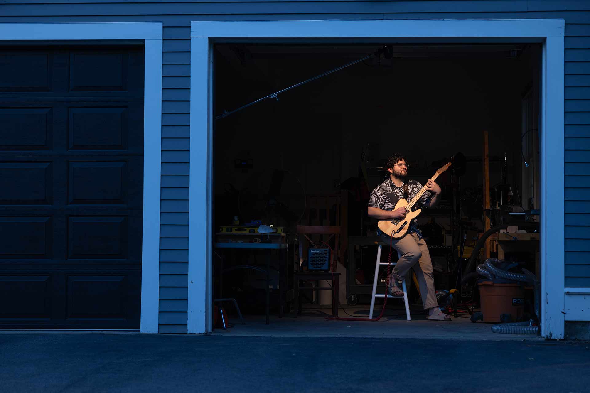 Sam Aronson kneels down to eye-level with a table as he measures a guitar