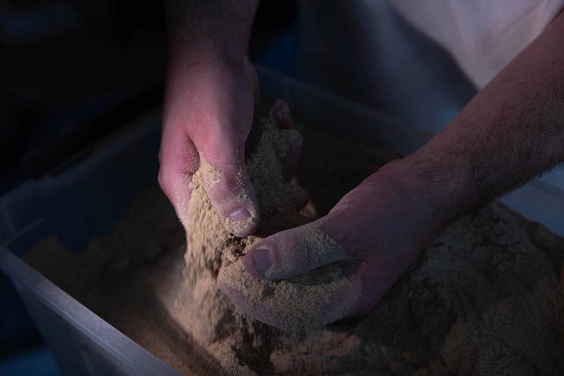 Dust covering two hands, falling into a bin