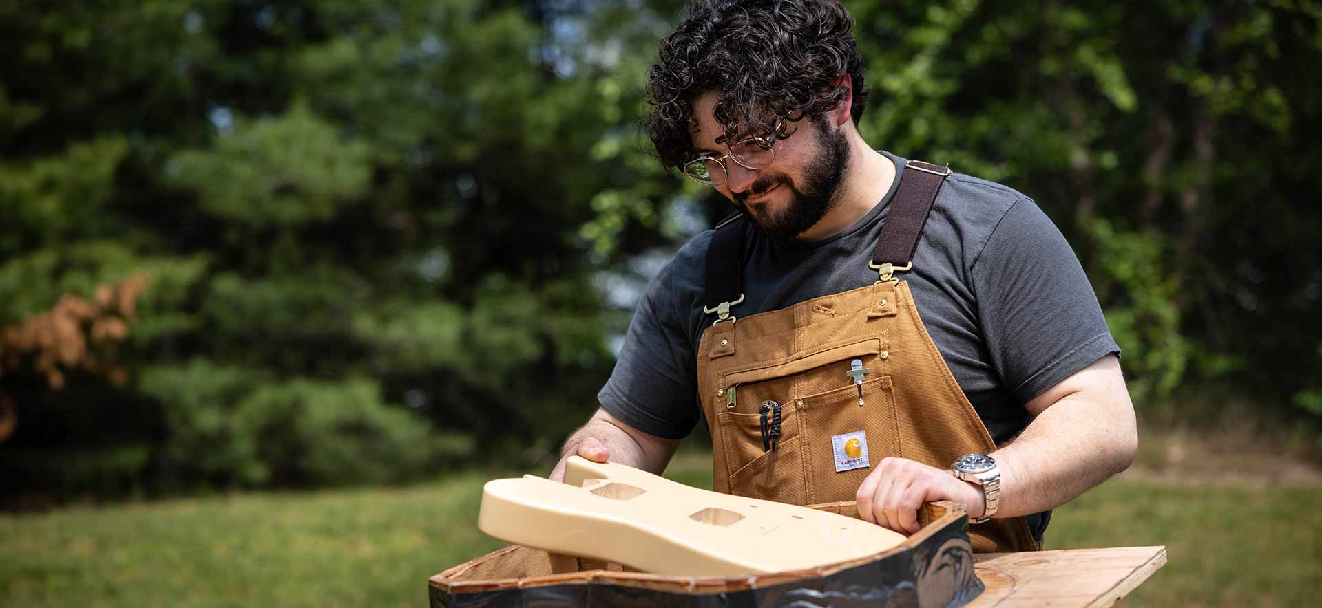 Sam resting a guitar prototype on a table outside