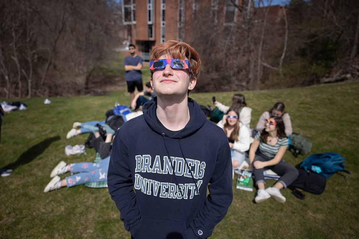 Person wearing eclipse glasses looks toward the sky