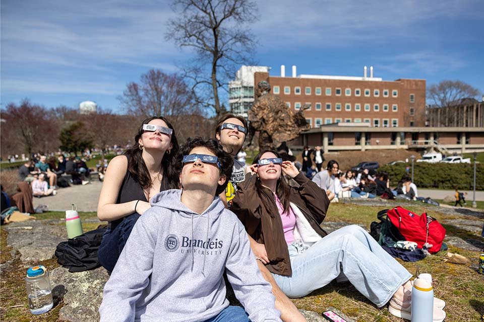 Students look up toward the sky wearing protective glasses