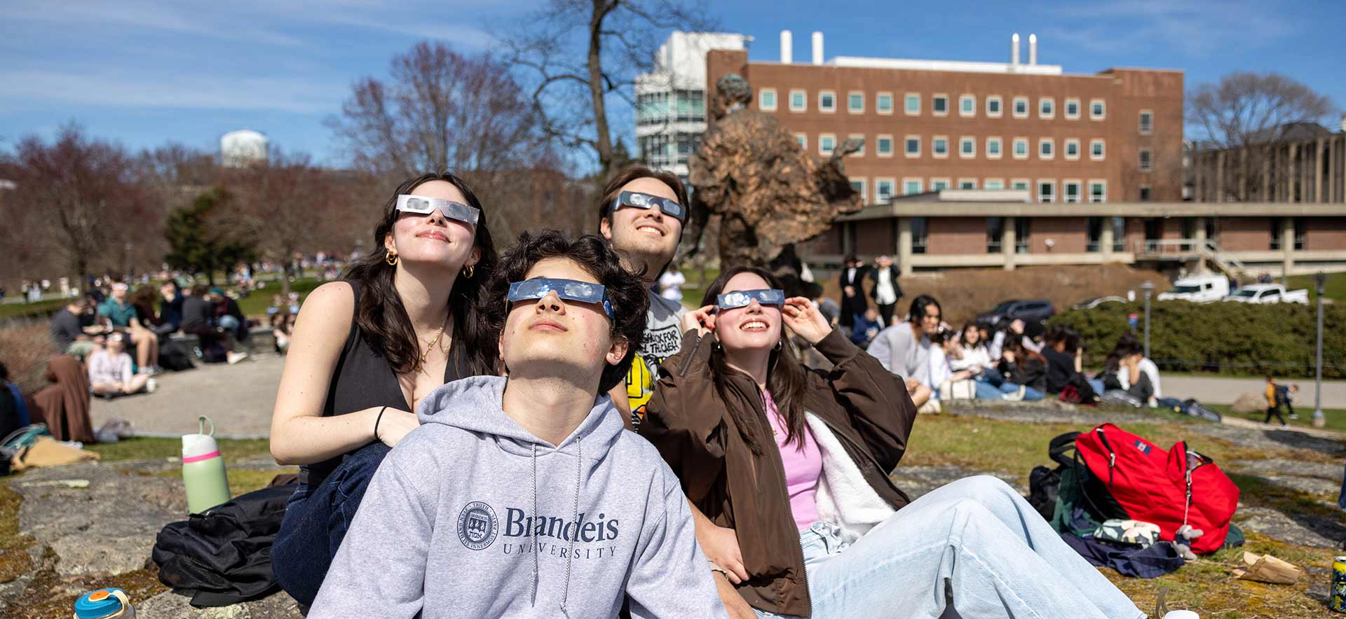 People wearing eclipse glasses on the Brandeis campus