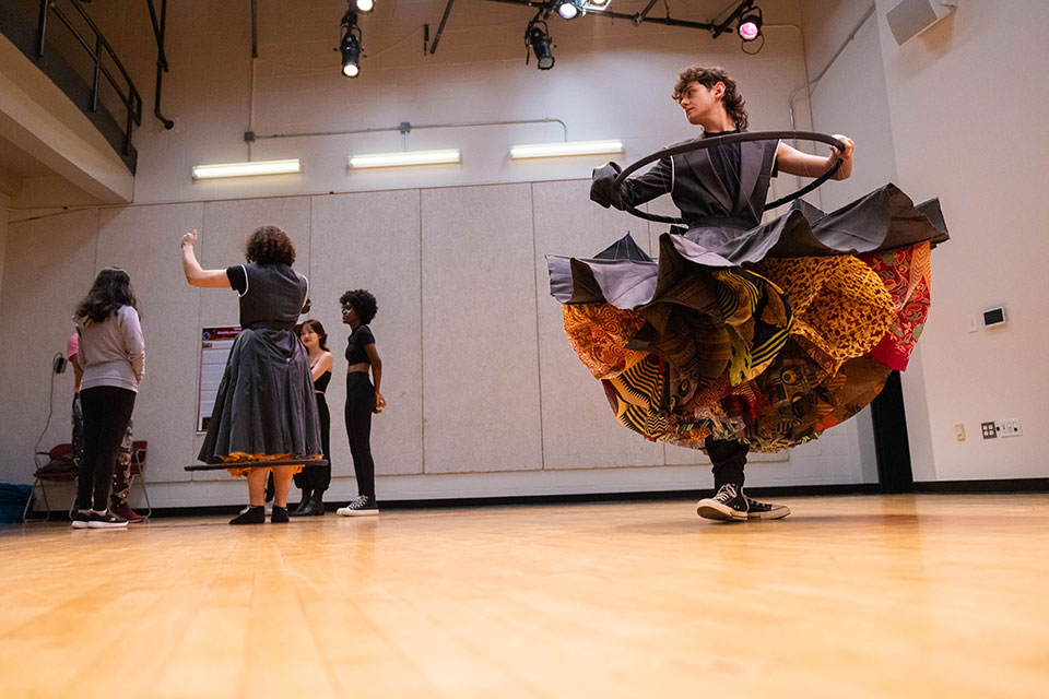 A students dances dressed in a costume featuring a colorful skirt.