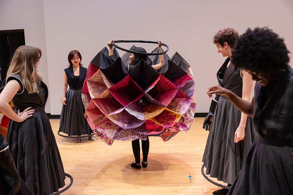 A student displays their colorful skirt while other students look on.