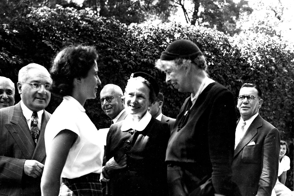 Eleanor Roosevelt speaks with a student as a group of people, including Abram Sachar, look on.