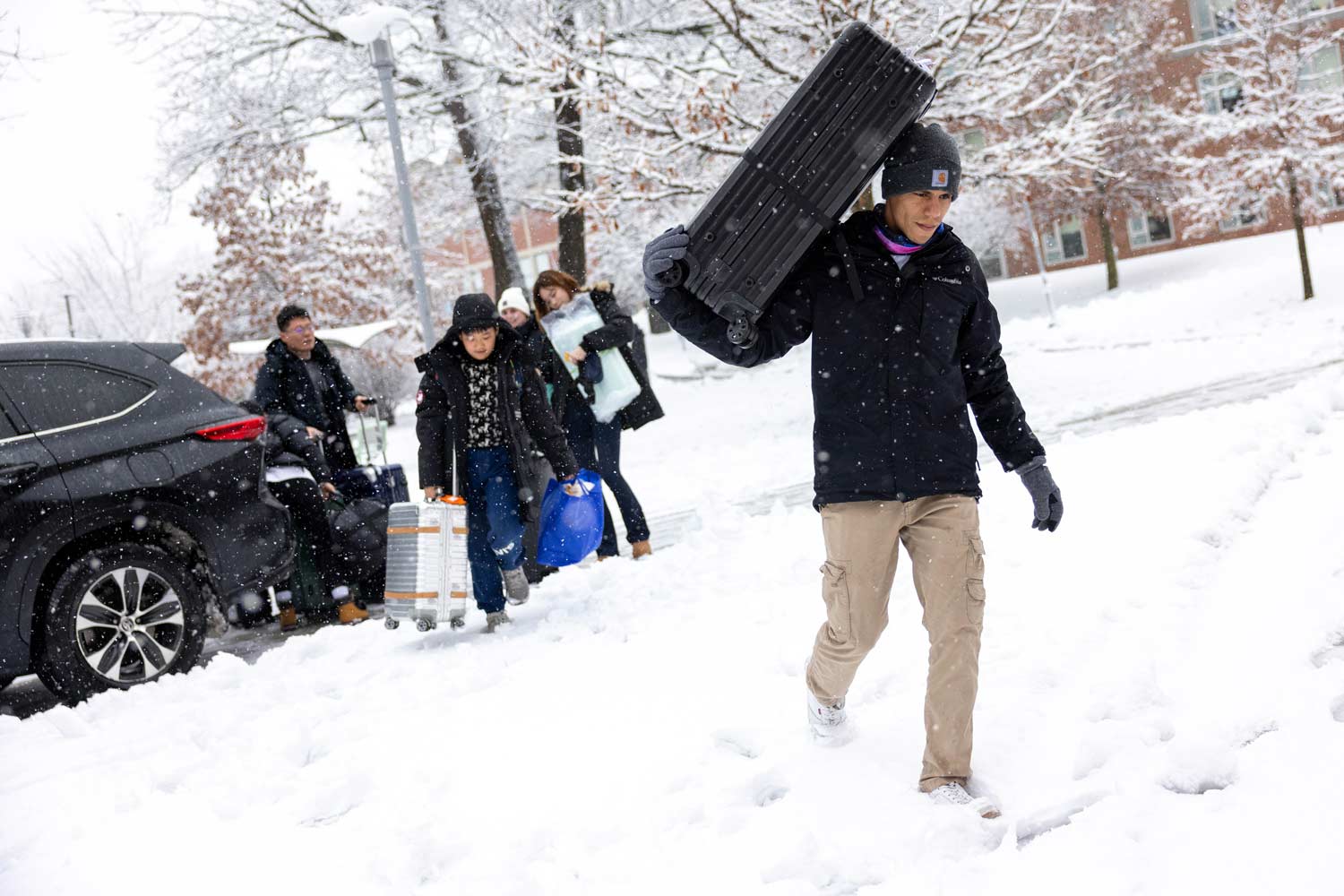 Student carrying luggage through snow