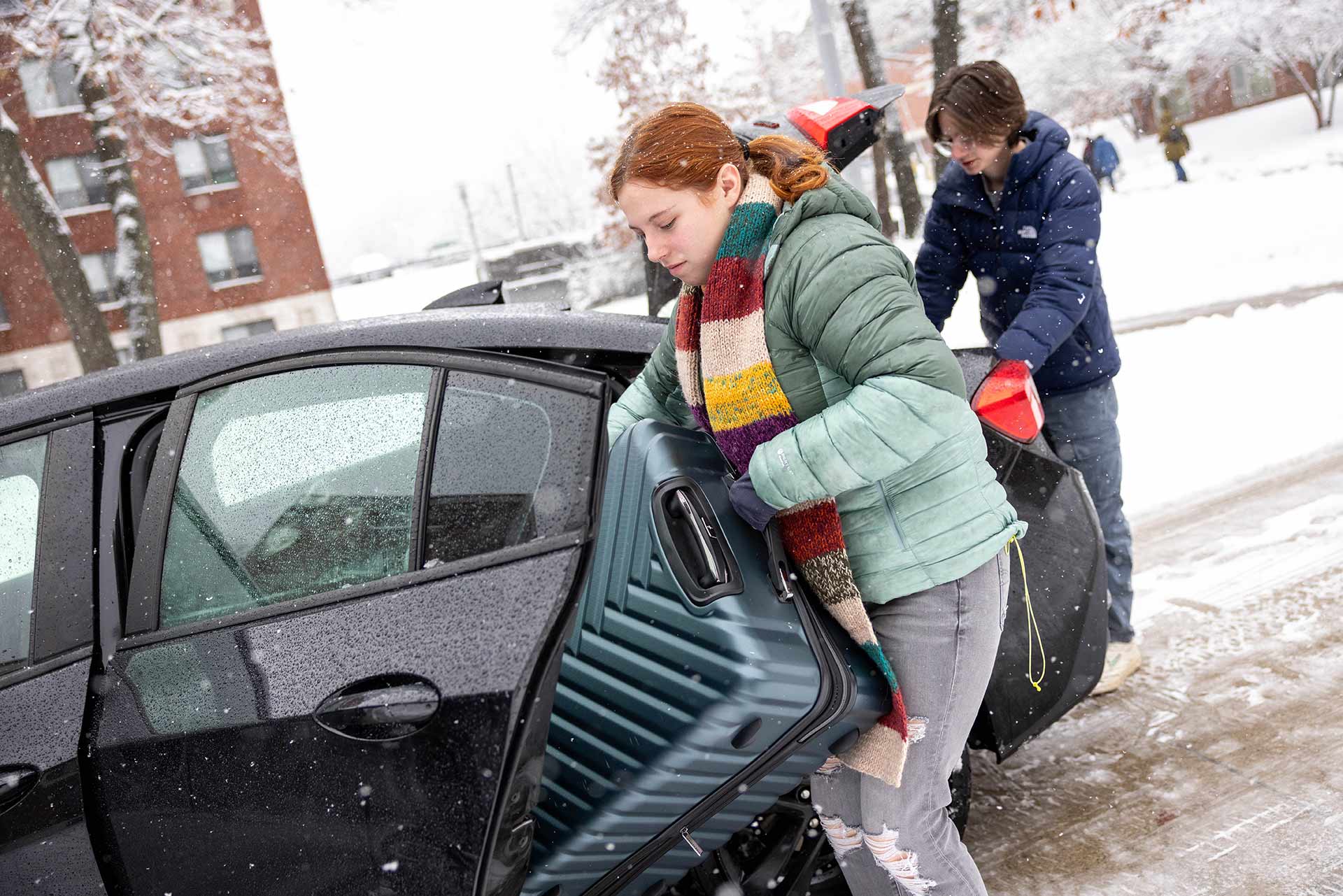 A student pulls a suitcase from car