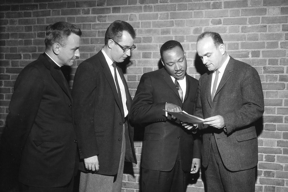 Martin Luther King Jr. examines a document with three other men.