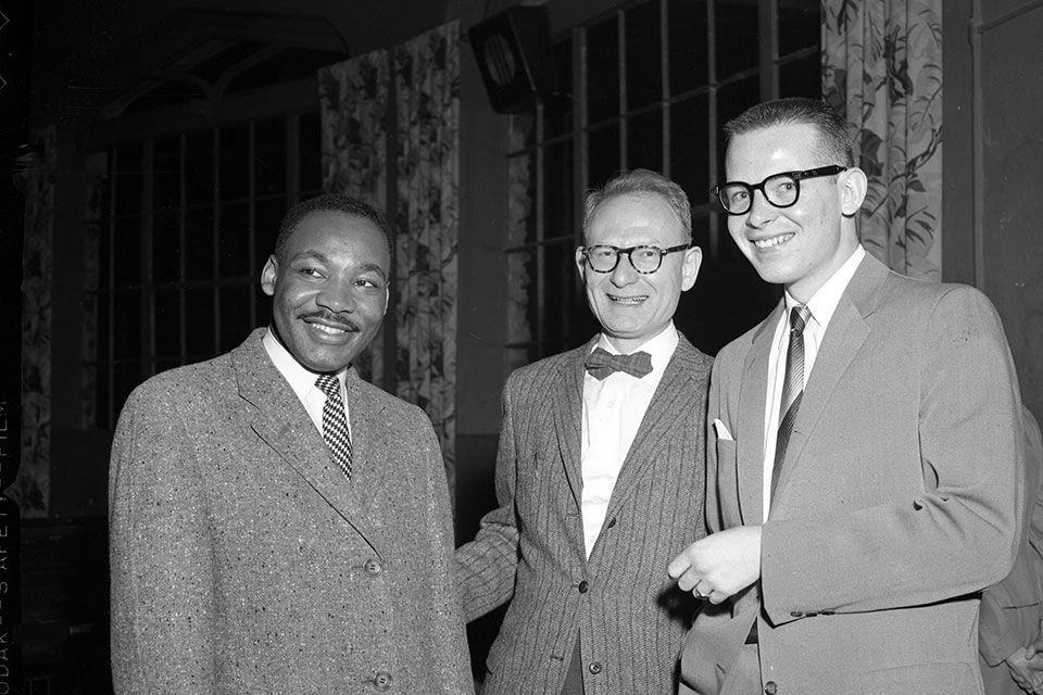 Martin Luther King Jr. smiles with two other people on his visit to Brandeis University.