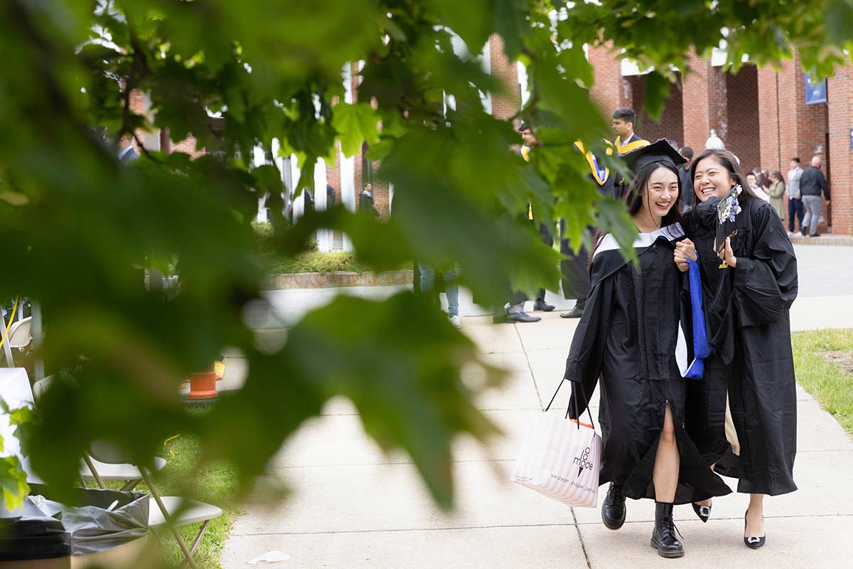 Two graduates walking through campus before Commencement