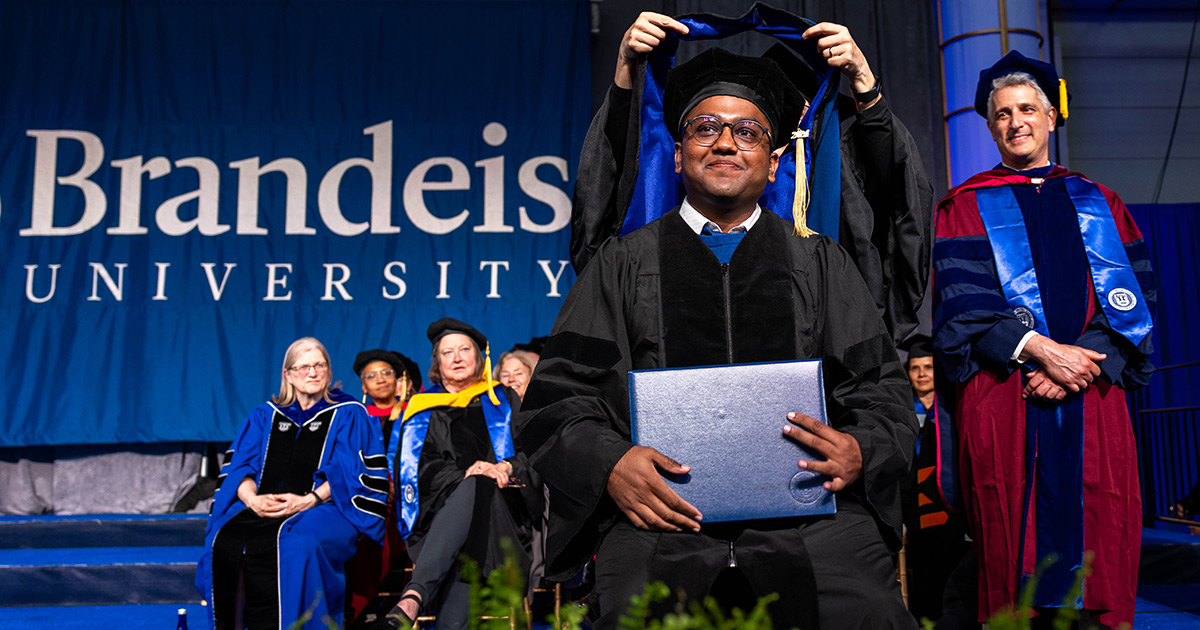 A graduate student receives his hood at Commencement